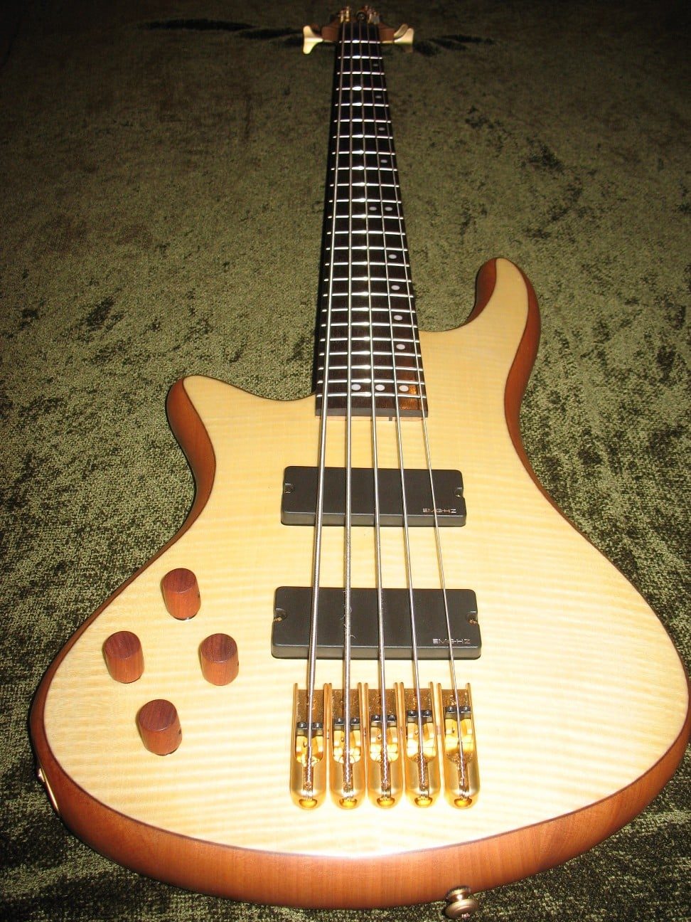 Left-handed six-string bass with a flamed maple top, gold bridge and wooden control knobs