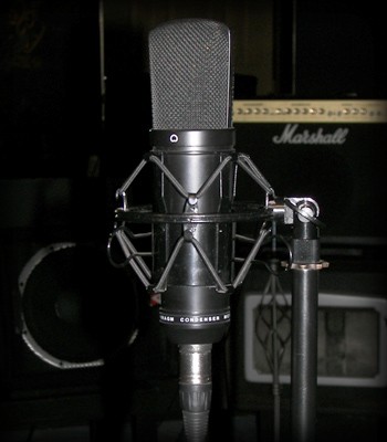 Large studio condenser microphone in a shock mount with a Marshall guitar amp behind it