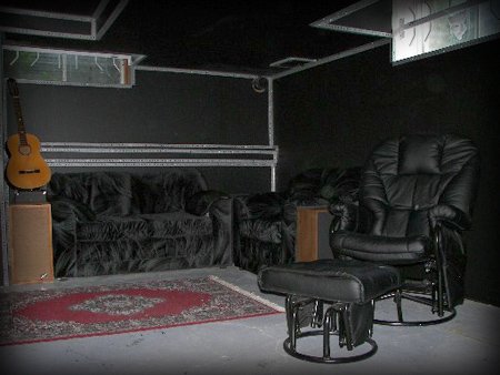 Studio lounge with black leather sofas and walls trimmed in corner bead